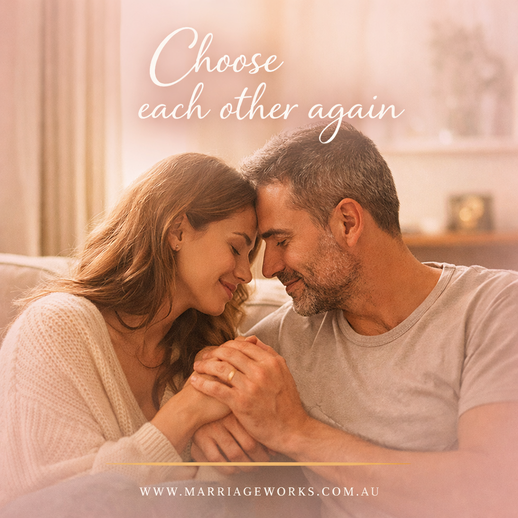 A couple sitting close together on a couch in warm, soft light, gently holding hands and leaning their foreheads together with eyes closed. The image conveys intimacy, emotional connection, and calm reconnection. Text overlay reads “Choose each other again” with www.marriageworks.com.au at the bottom.
